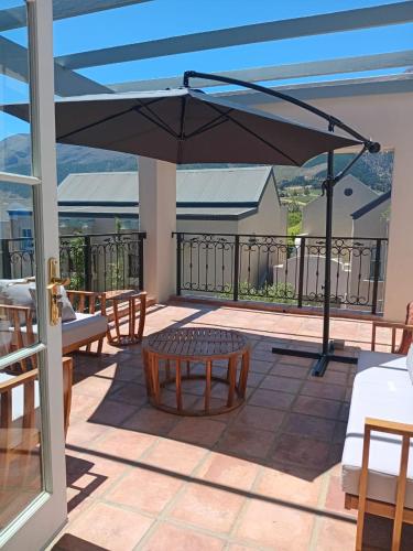 een patio met een tafel en een parasol bij L'Ermitage Villa Francois in Franschhoek