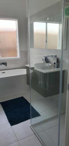 a bathroom with a sink and a tub and a mirror at Quiet Spacious Room in a Shared Family Home in Yarrabilba in Plunkett Station