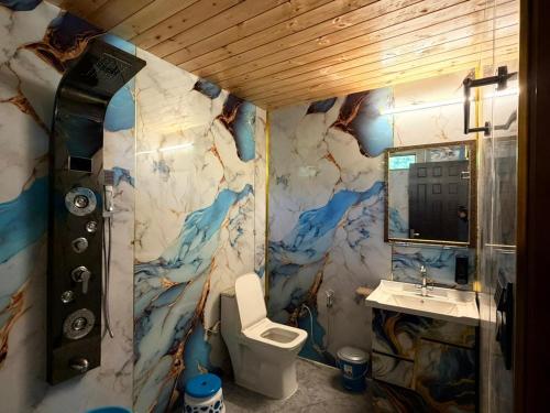 une salle de bain avec un mur en marbre avec des toilettes et un lavabo dans l'établissement Jolly Retreat, à Jhājra