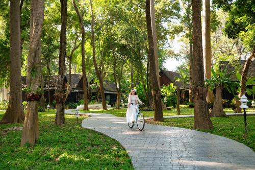 a woman riding a bike down a path in a park at Lampang River Retreat in Lampang