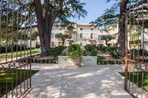 an entrance to a building with a gate and trees at Boutique Hôtel La Villa MONTESQUIEU in Laudun