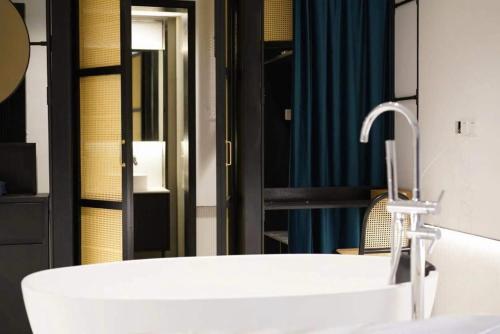 a bathroom with a white sink and a mirror at Grey Parrot Resort Hotel in Chengdu