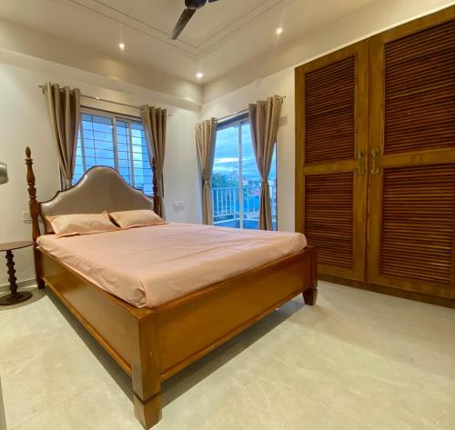 Schlafzimmer mit einem Bett mit Holzschränken und Fenstern in der Unterkunft Go-Kul Home Stay in Kolhapur