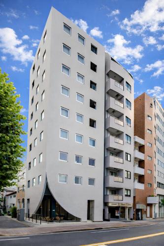 a white building with a curvilinear facade at STAY ARI Shinjuku Takadanobaba Design awarded in Tokyo