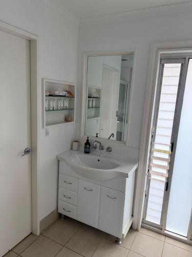 a white bathroom with a sink and a mirror at Harrington Haven in Harrington
