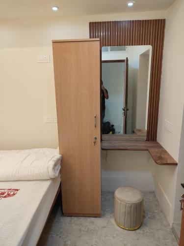 a bedroom with a bed and a mirror and a stool at Nisarga Comforts in Chikmagalūr