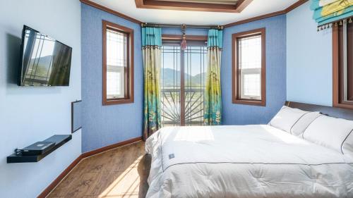 ein Schlafzimmer mit einem Bett und einem großen Fenster in der Unterkunft Samcheok Duelkkot Pension in Samcheok