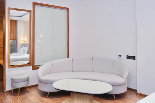 een woonkamer met een witte bank en een spiegel bij Le OVAL Hotel & Resorts in Nakraunda