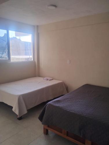 two beds in a room with a window at Apartamentos Turiksa in Acapulco