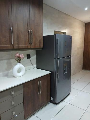 a kitchen with a refrigerator and a vase with flowers in it at Mhlezi Lodge in Richards Bay