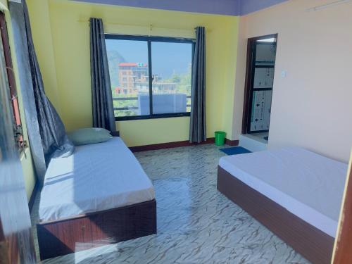 a bedroom with two beds and a large window at Hotel Forest Side in Bandīpur