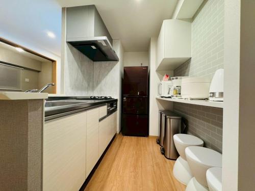 a small kitchen with white cabinets and a sink at LuxurySweet East71 最大7人 ペット可 箱崎宮前駅徒歩3分 新築 in Fukuoka