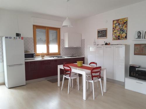 a kitchen with a table and chairs and a white refrigerator at Casa Isabella in Calasetta