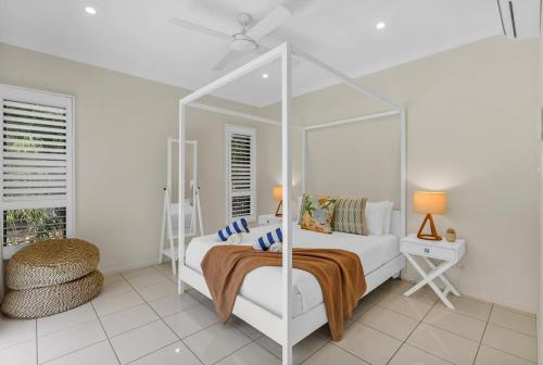 a white bedroom with a bed and a mirror at Belle Escapes Sandcastles in Palm Cove