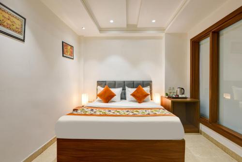 a bedroom with a large bed with orange pillows at Qotel Comfort Ashok Vihar in New Delhi