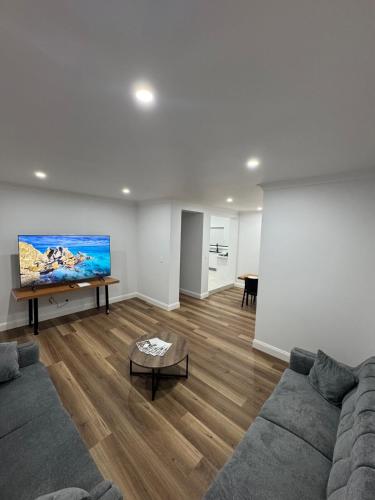 a living room with a couch and a flat screen tv at HOME away from HOME in Sydney