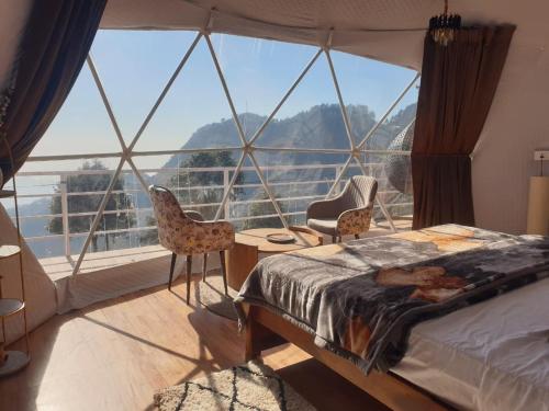 ein Schlafzimmer mit einem Bett und einem großen Fenster in der Unterkunft D'Resort in Masuri