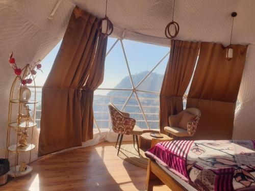 ein Schlafzimmer mit einem großen Fenster mit einem Bett und einem Stuhl in der Unterkunft D'Resort in Masuri