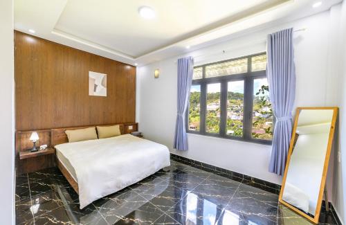 a bedroom with a bed with blue curtains and a mirror at Cocovilla Đà Lạt in Ấp Ða Lợi