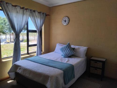 a bedroom with a bed and a clock on the wall at Magic Flame farm in Hopefield