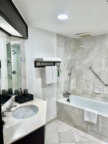 a bathroom with a sink and a bath tub at Sabah Hotel in Sandakan