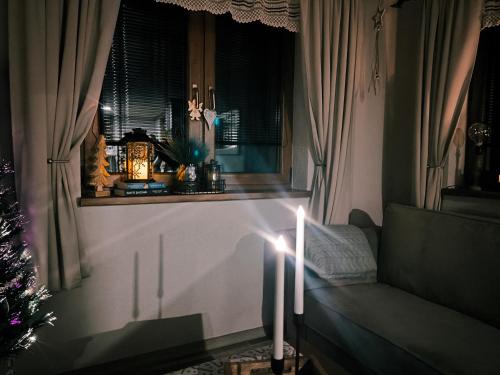 a candle in front of a window with a christmas tree at Na Divokom Vŕšku in Jamník