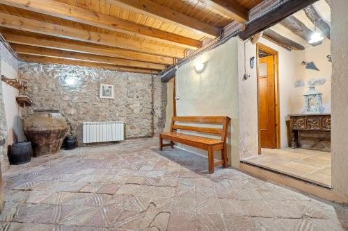 een gang met een houten bank in een kamer met een stenen muur bij Cal Marti in Farena