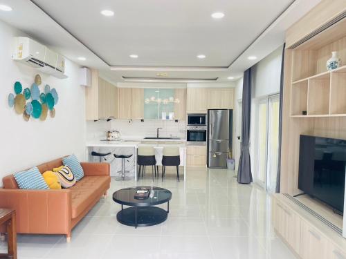 a living room with a couch and a table and a kitchen at 3BR Pool Villa Beach Access Patumnak Hill in Pattaya South