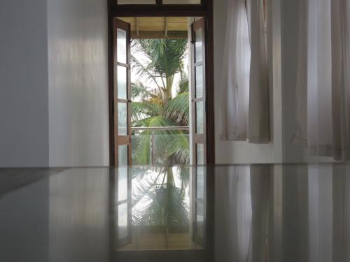 an empty room with a door and a palm tree at Paradise Bay in Beruwala