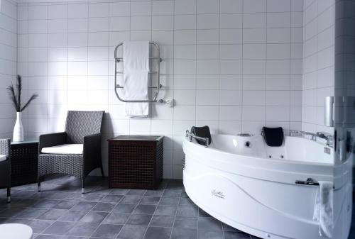 a white bathroom with a tub and a chair at Hotell Björkhaga in Mullsjö