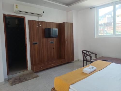 een slaapkamer met een bed en een kast met een televisie bij The JRS Hotel in Rishīkesh