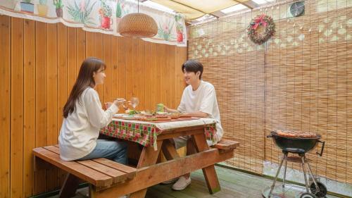 een man en een vrouw zitten aan een tafel en eten bij Pocheon Arumdri Pension in Pocheon