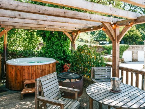 eine Terrasse mit einem Whirlpool, einem Tisch und Stühlen in der Unterkunft The Game Keeper - Uk50611 in Appletreewick