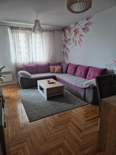 ein Wohnzimmer mit einem lila Sofa und einem Couchtisch in der Unterkunft Anja in Lukavica
