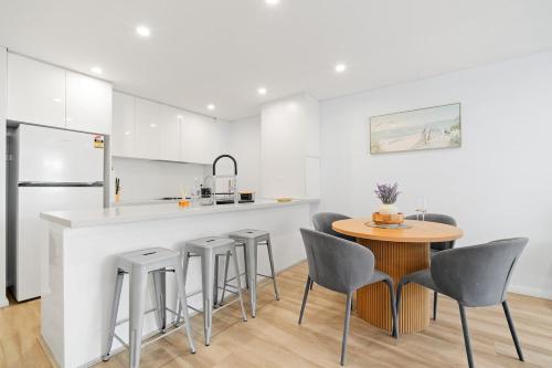 a kitchen with a counter and a table and stools at Luxury 2Bed 2bath Apartment with Distance Harbour Bridge View 6km from CBD in Sydney