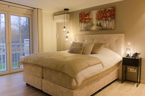 ein Schlafzimmer mit einem Bett und einem Gemälde an der Wand in der Unterkunft Bed and Breakfast L'Orée Du Bois in Wavre