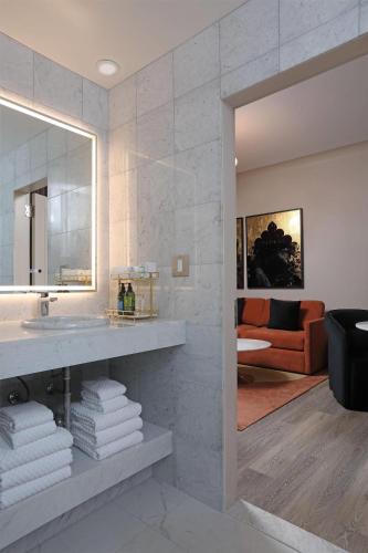 a bathroom with a sink and a mirror and a couch at The Fort Garry Hotel, Spa and Conference Centre, an Ascend Collection Hotel in Winnipeg