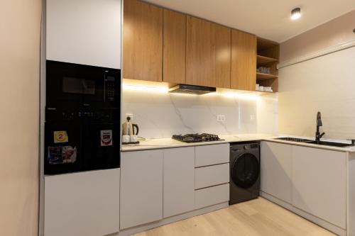 a kitchen with white cabinets and a black refrigerator at FTM Residence in Abuja