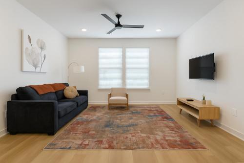 ein Wohnzimmer mit einer schwarzen Couch und einem Fernseher in der Unterkunft A plus Location WorkerFriendly KINGbed Pool Gym Modern in Sherman