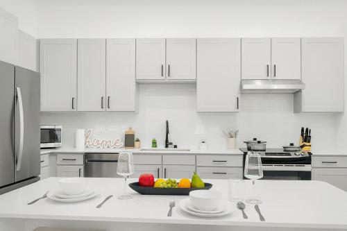 a white kitchen with a bowl of fruit on a counter at Modern A plus Location KINGbed pool gym in Sherman