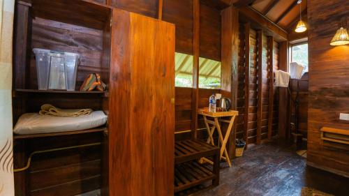 a room with a wooden cabin with a bed and a table at Chena Huts Eco Resort in Sigiriya