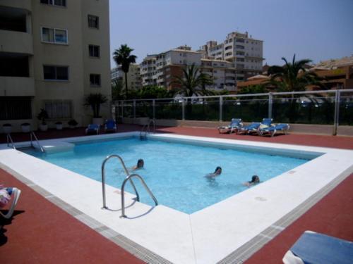 three people in a swimming pool in a building at Apartamento Puerto Deportivo in Estepona