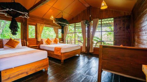 a bedroom with two beds in a room with windows at Chena Huts Eco Resort in Sigiriya