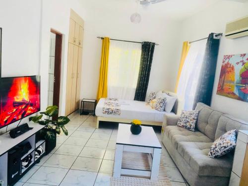 een woonkamer met een bank en een tv bij Tash Studios in Diani Beach