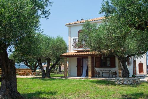una casa bianca con alberi di fronte di Oliva Cottage - Ideal for Families Close to Zakynthos Town a Città di Zante