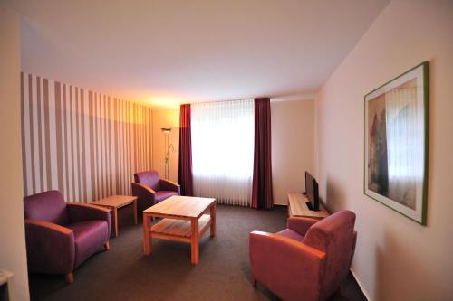 a hotel room with chairs and a table and a tv at Gästehaus Wacholderheide Garni in Eimke