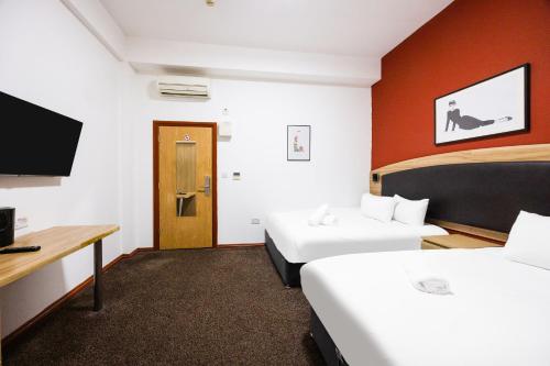 a hotel room with two beds and a flat screen tv at Arinza Hotel, London Ilford in Ilford
