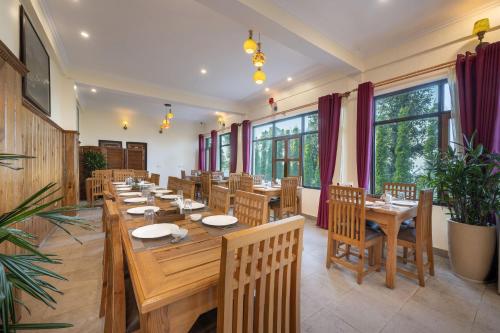 un ristorante con tavoli e sedie in legno e finestre di Echor Himalayan Retreat Ranikhet a Rānīkhet