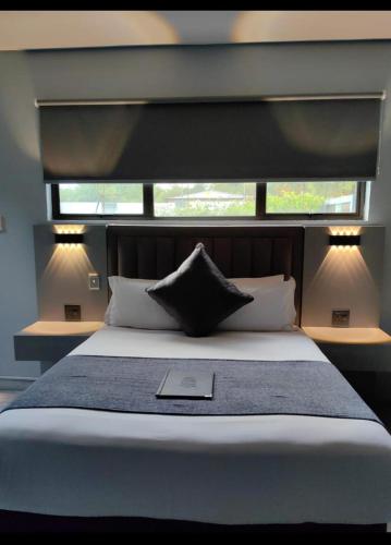 a bedroom with a large bed with two windows at Pula Nala Lodge in Rustenburg