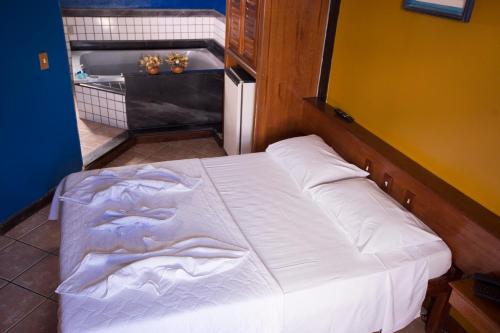 Cama blanca en habitación con baño en Porto Marlin Hotel, en Conceição da Barra